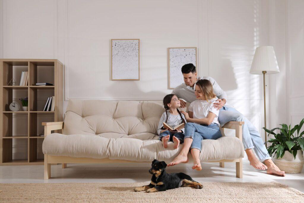 Glückliche Familie auf dem Sofa und Welpe im Wohnzimmer