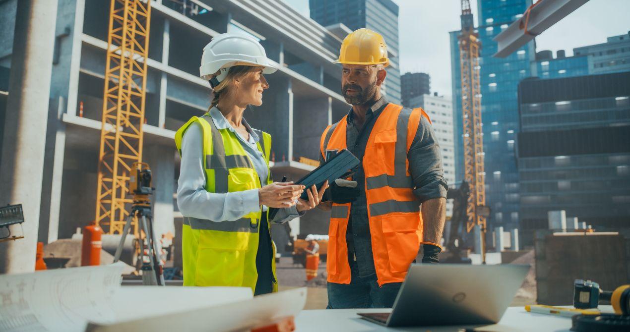 Zwei Ingenieure auf einer Großbaustelle besprechen die Planung moderner Infrastrukturprojekte unter Verwendung von GFK-Rohr.