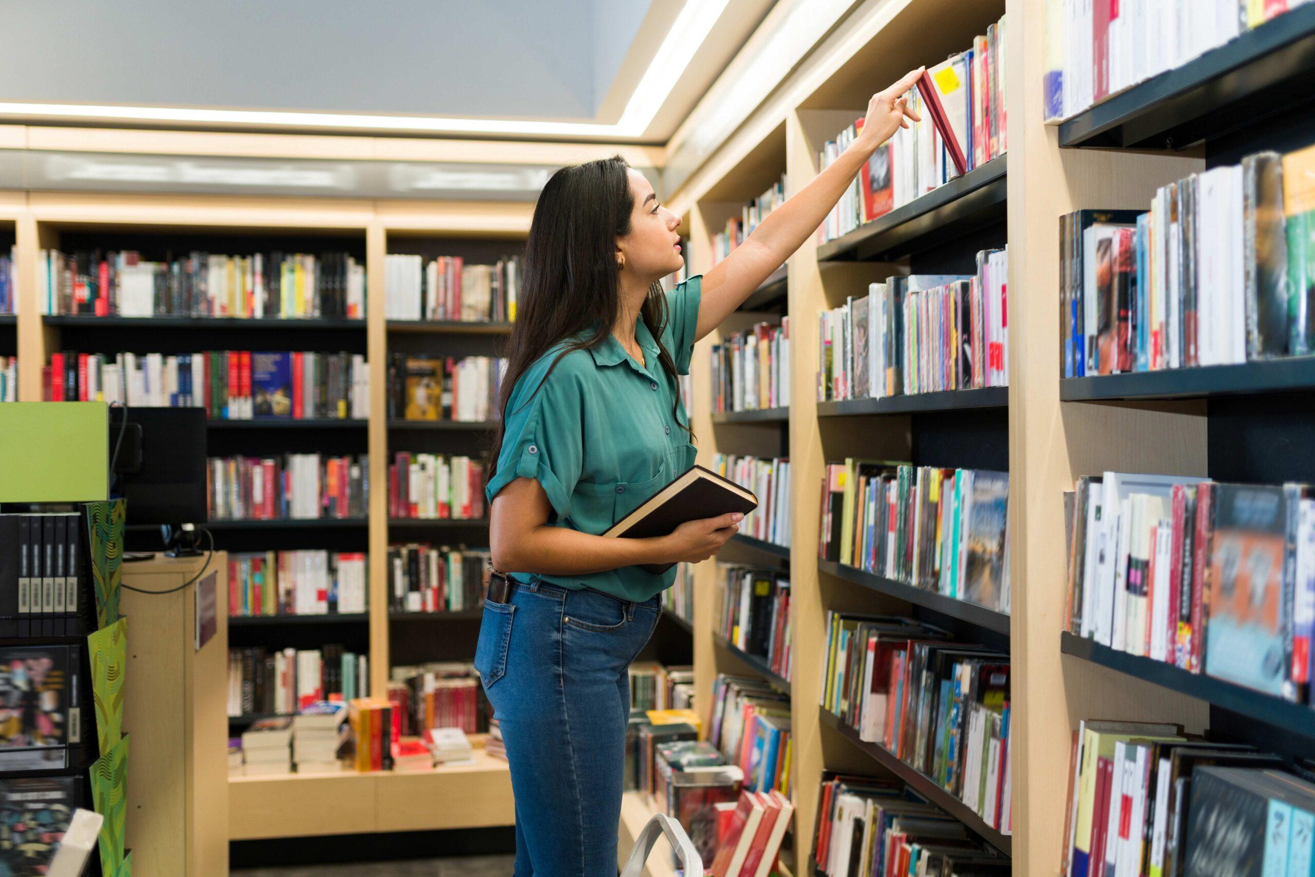 Attraktive Frau, die ein Buch in den Bücherregalen des Ladens auswählt