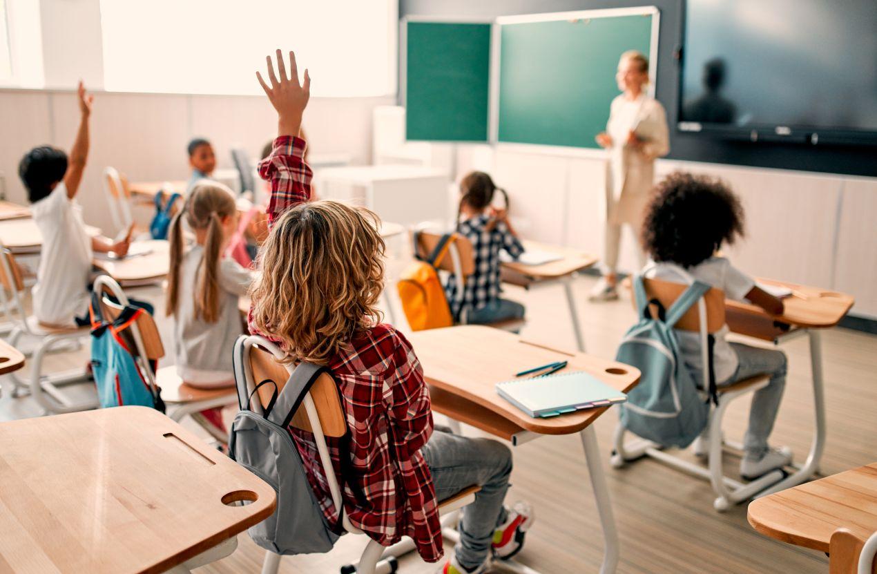 Schueler im Klassenzimmer heben die Hand – aktiver Unterricht an einer Berlin Privatschule mit digitaler Ausstattung