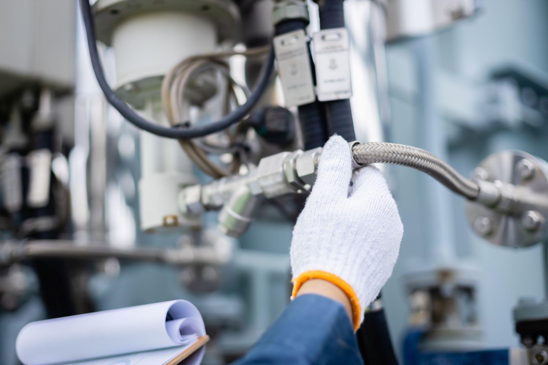 Fachkraft montiert mit Handschuhen einen Hydraulikschlauch – Symbolbild für den präzisen und sicheren Einsatz von Schnellkupplungen in der Industrie