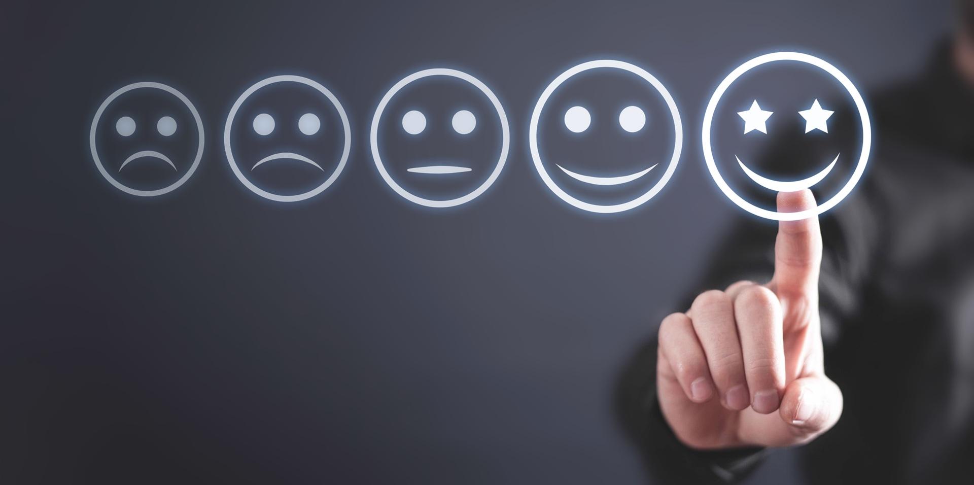 Hand tippt auf lächelnden Smiley mit Sternen zur Bewertung | Baufinanzierung Mönchengladbach